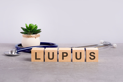 wooden block form the word Lupus with stethoscope on the doctor's desktop. medical concept - light gray backgrond. healthcare conceptual for hospital, clinic and medical business.