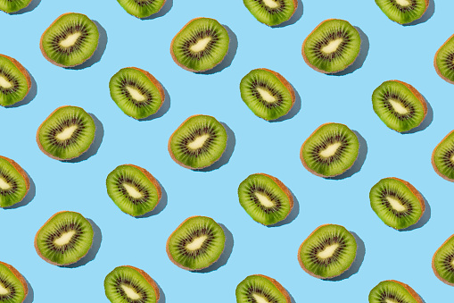 Pattern of fresh kiwi slices on pastel blue background. Minimal  tropical fruit concept. From top view.