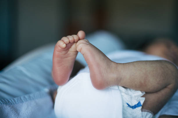 The tiny foot of a newborn baby. Soft feet of a new born in a wool white blanket. Close up of toes, heels and feet of a newborn. Macro photography.