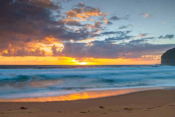 istock Sunrise at the seaside with waves and clouds 1368841670