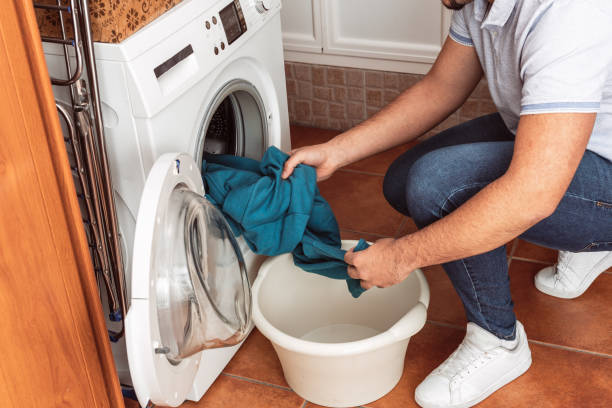 istock a man taking a blue sweatshirt out of the washing machine 1368842025