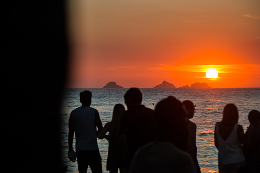 silhouette of people watching the sunset at arpoador beach in rio de janeiro, brazil.