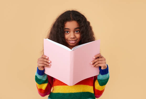istock Smiling ethnic schoolgirl reading book 1368847887
