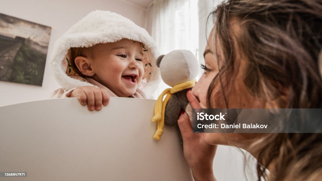 Childcare. Mother playing with baby at home. Babysitting one year old baby girl at home. Nanny Stock Photo