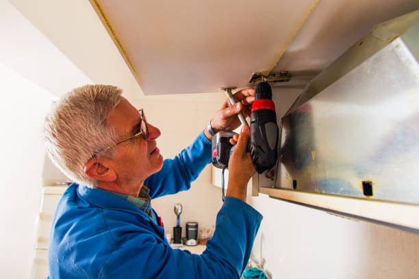 Senior workman working with power drill Mature serviceman is standing in the kitchen and working with power drill on cupboard holding drill stock pictures, royalty-free photos & images