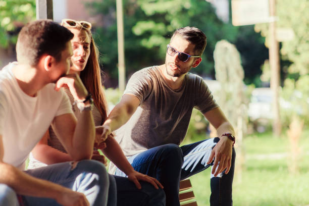Group of three cheerful friends while sitting on summer time in the city