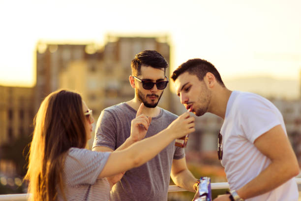 Portrait of young friends  amuse on rooftop of the building Three attractive friends having fun on the balcony at sunset amuse stock pictures, royalty-free photos & images