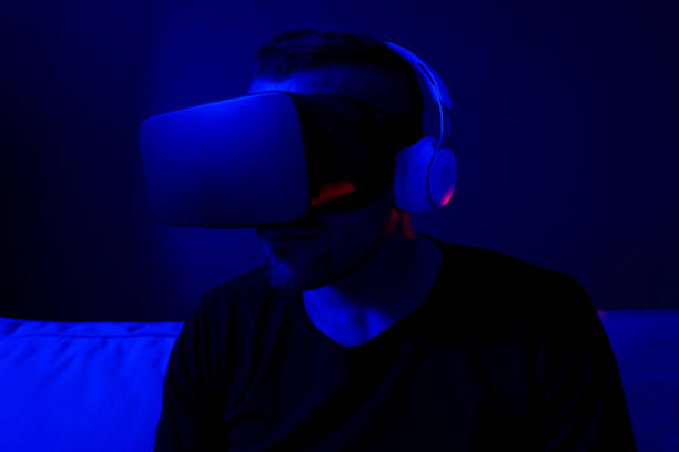 istock Man wearing virtual reality goggles watching 360 degree video  on dark background. Blue neon light. Close-up. 1368854960