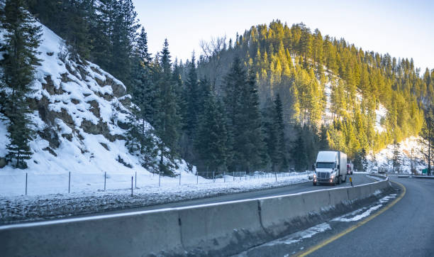 istock Big rigs semi trucks with semi trailers transporting cargo climbing in convoy on the winding winter highway road with snow and ice in Montana mountains 1368856575