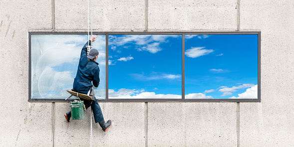 window washer with sky reflection, panoramic frame