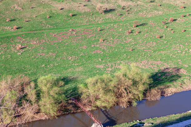 Footbridge over the river view from above . Aerial view of riverside and meadow