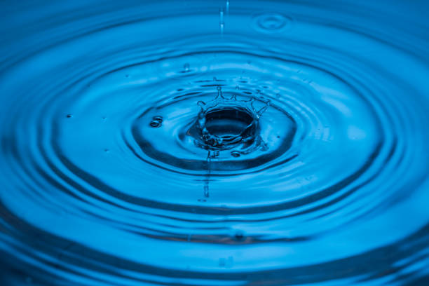 3d render. Close-up of a blue water droplet captured in mid-air as it splashes, surrounded by concentric ripples, emphasizing purity, freshness, and the beauty of natural elements.