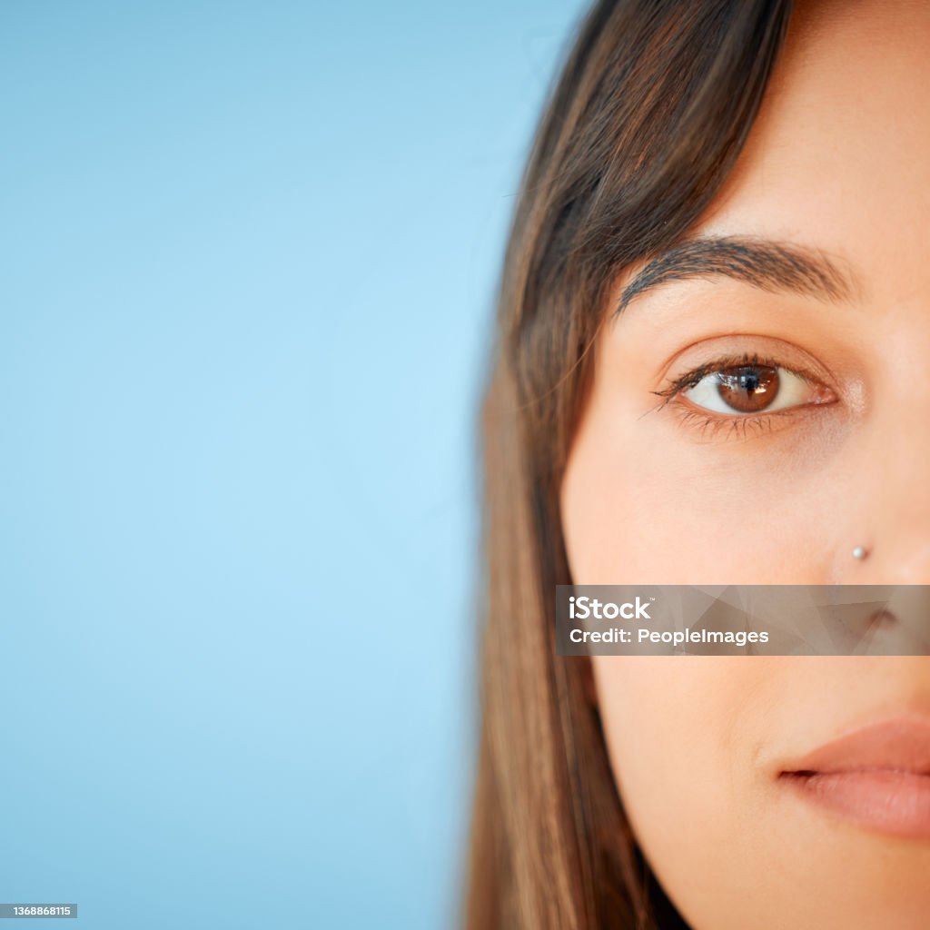 Closeup portrait of a beautiful young woman against a blue background Simply lovely Nose Ring Stock Photo