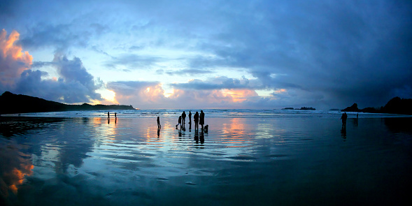 people in silhouette beach at dusk, panoramic frame