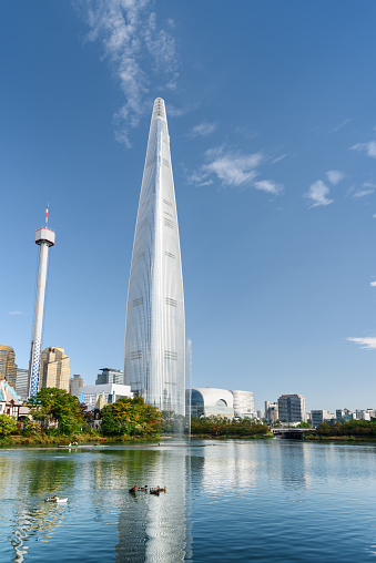 Beautiful view of skyscraper reflected in water at downtown of Seoul, South Korea. Scenic cityscape with modern tower. Flock of ducks is visible on lake. Seoul is a popular tourist destination of Asia