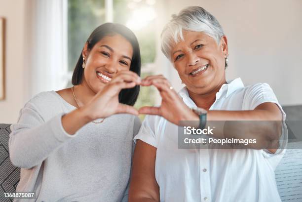 Portrait Of A Mother And Daughter Holding Their Hands Together To Form A Heart Shape On The Sofa At Home Stock Photo - Download Image Now
