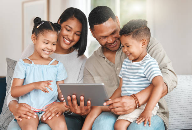 istock Shot of a young family happily bonding while using a digital tablet together on the sofa at home 1368877509
