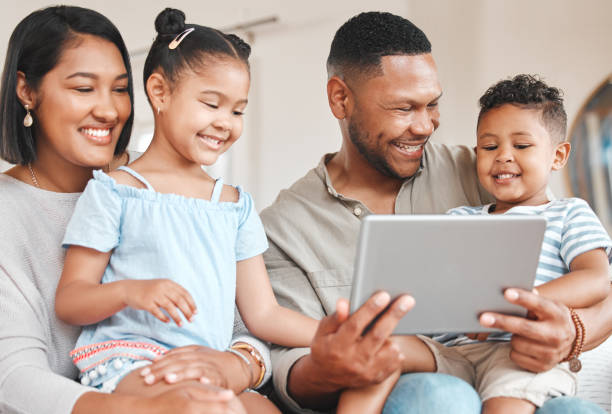 istock Shot of a young family happily bonding while using a digital tablet together on the sofa at home 1368877511