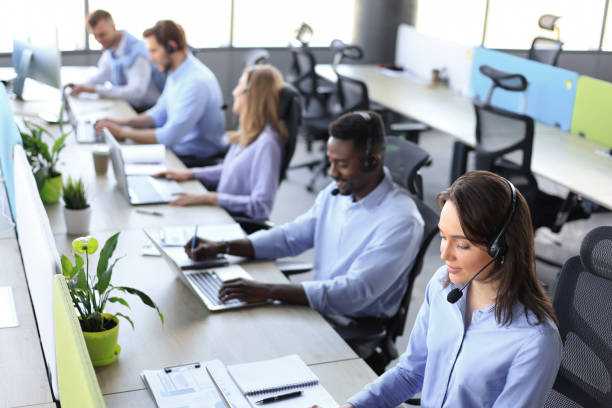 istock Young employee working with a headset and accompanied by her team 1368883532