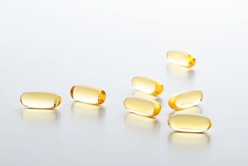 Close up of yellow gel capsules on white background.