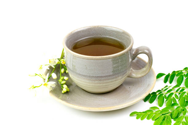Moringa Tea in gray ceramic cup with fresh green leaf and flower isolated on white background. Moringa Tea in gray ceramic cup with fresh green leaf and flower isolated on white background. Moringa oleifera tropical herb healthy lifestyle concept. isolated color stock pictures, royalty-free photos & images