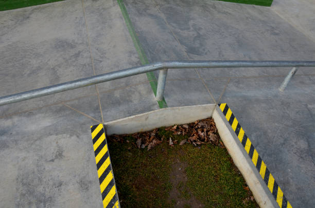 Skateboard park with concrete cement surface with concrete skateboard obstacles is designed for roller sports. Cycling is not allowed except for freestyle bikes. Protective clothing, head, elbow knee, skateboarder, children, teenager, cycling, jump, bmx, stripes, striped, yellow, line