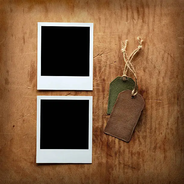 Two blank picture frames with two gift tags on old vintage wooden background.