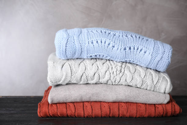 istock Stack of folded warm sweaters on black wooden table 1368898271