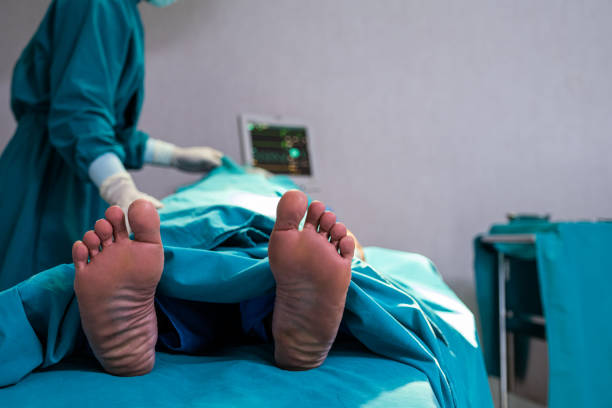 Selective focus at feet of pass away patient while doctor covering face inside of the surgery operation room in the hospital. Illness and death concept. Selective focus at feet of pass away patient while doctor covering face inside of the surgery operation room in the hospital. Illness and death concept. dead stock pictures, royalty-free photos & images