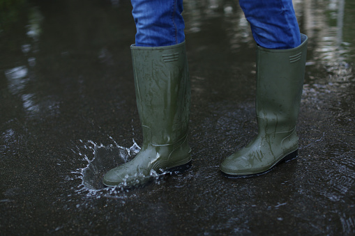 Man in rubber boots walking on wet street after rain, closeup