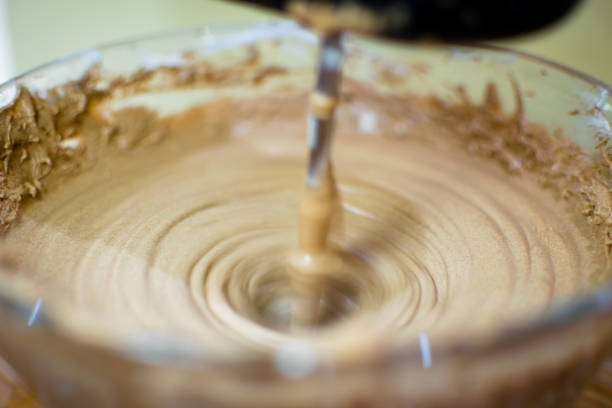 Making of ice cream by blending cocoa powder with cream. Blending the mixture by using blender rotating fast in circular. Used selective focus.