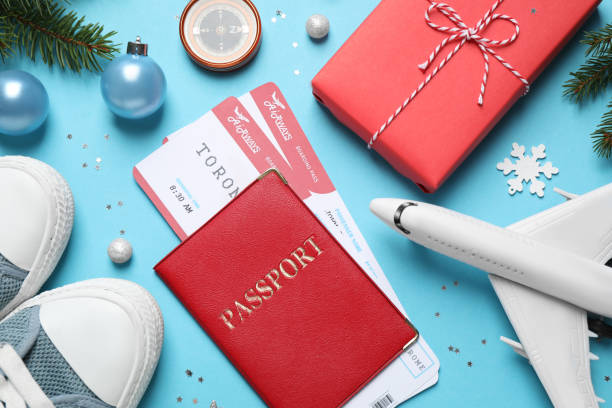 istock Flat lay composition with Christmas decorations, passport and airline tickets on light blue background. Winter vacation 1368903383