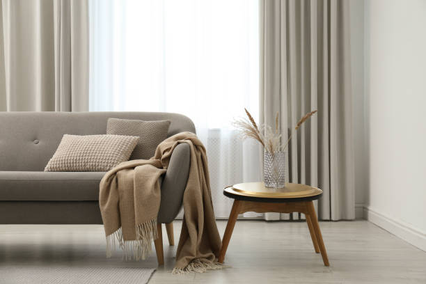 istock Grey sofa with pillows near window in stylish living room interior 1368908393