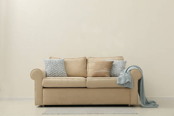 istock Comfortable sofa near beige wall in living room interior. Space for text 1368909593