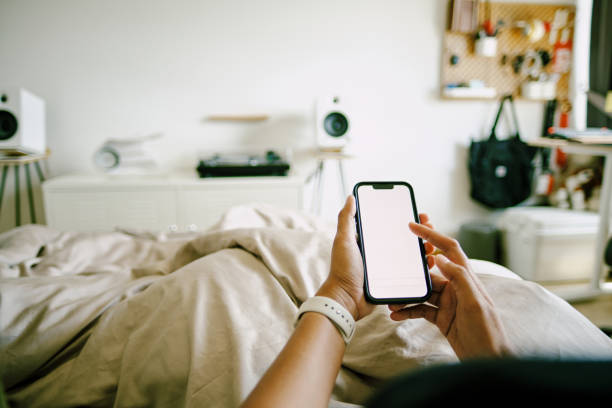 istock Young woman using smart phone while laying in bed at home 1368909630