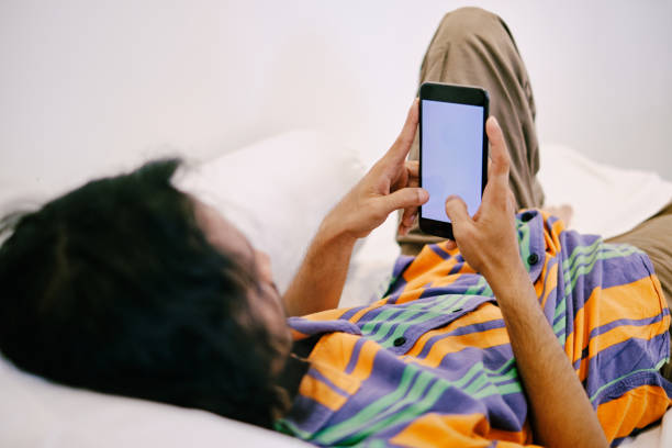 istock Young man using smart phone while laying in bed at home 1368909635