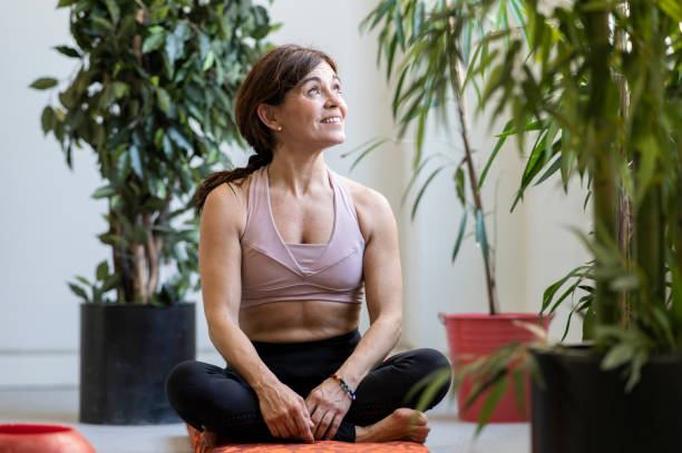 istock pretty older woman smiling while practicing yoga 1368909778
