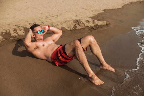 istock A buff and confident man does abdominal crunches by the beach. Training and working out at a leisurely pace at a resort or during a vacation. 1368910578