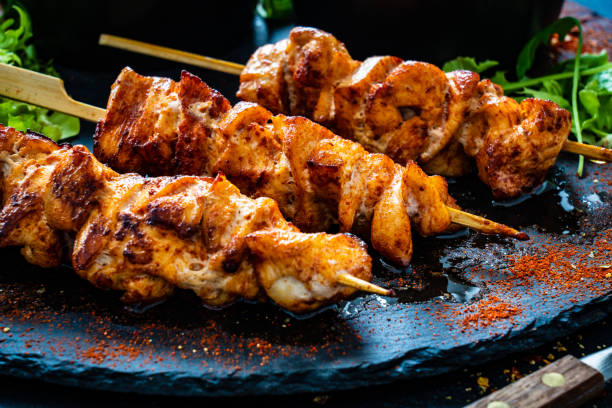 schaschlik - gegrilltes fleisch und gemüse auf steinplatte auf holztisch - grillhühnchen stock-fotos und bilder