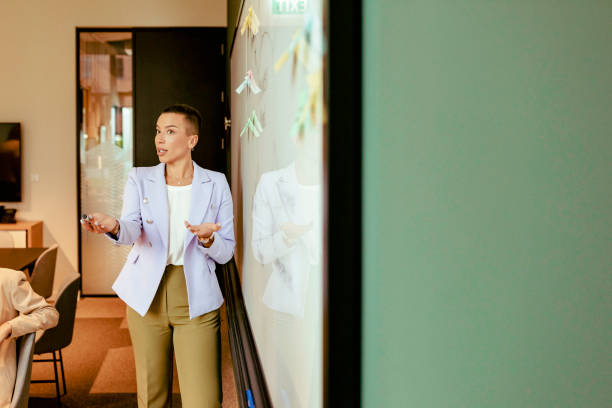 istock Business Woman Presenting in Front of a Whiteboard 1368912171