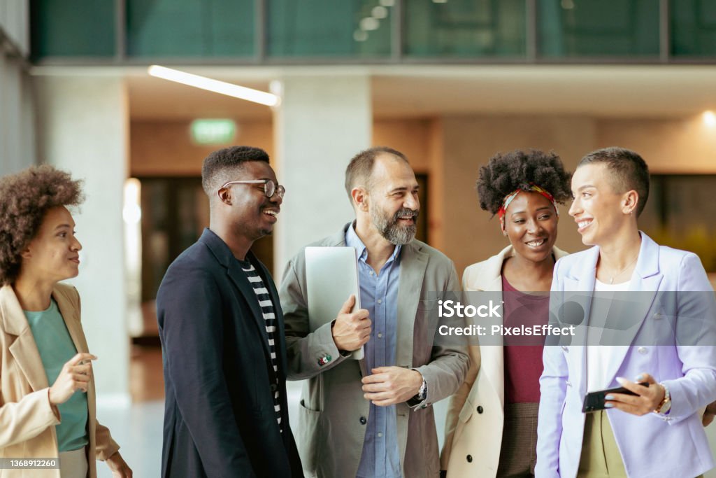 Winning Team Group of Diverse Coworkers Standing at the Office Corridor and Smiling while Having an Informal Conversation Employee Stock Photo