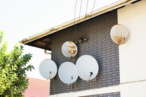 Satellite dishes in bad condition outside a residential building.