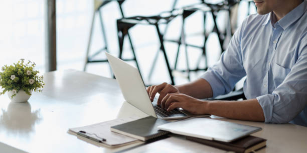 istock Smiling business man using laptop at office. Male hands typing on the notebook keyboard.Concept of young people work mobile devices 1368913196