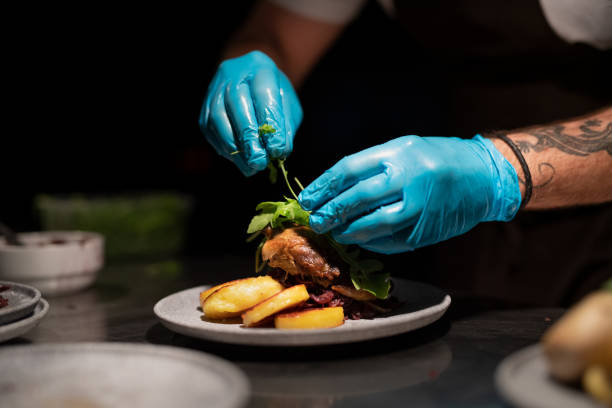 istock Chef's hands in gloves serving and decorating meal in restaurant kitchen 1368915556