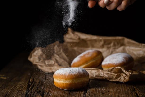 istock Donut filled with jam on black background, sprinkled with sugar. 1368916197