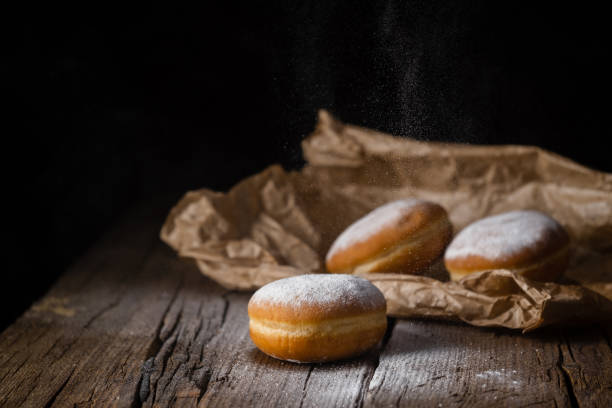 istock Donut filled with jam on black background, gently sprinkled with sugar. 1368916198