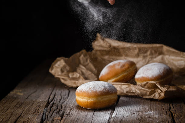 istock Donut filled with jam on black background, sprinkled with sugar. 1368916220