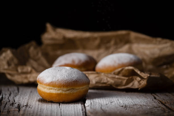 istock Donut filled with jam on black background, sprinkled with sugar. 1368916232