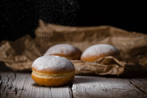 istock Donut filled with jam on black background, sprinkled with sugar. 1368916251