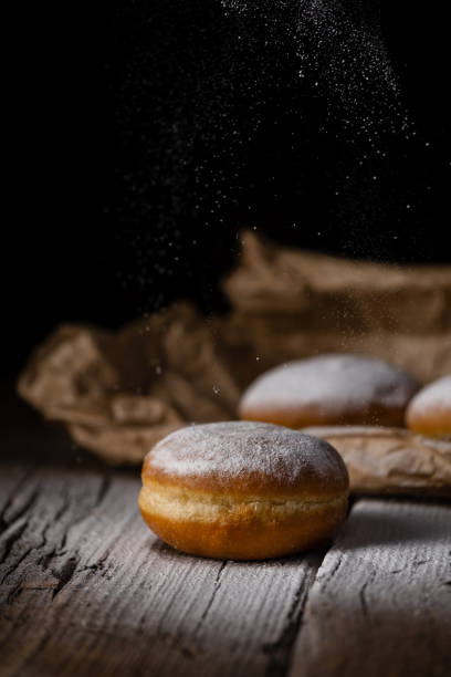 istock Donut filled with jam on black background, sprinkled with sugar. 1368916253
